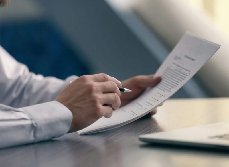 Documents a person holding a pen and paper
