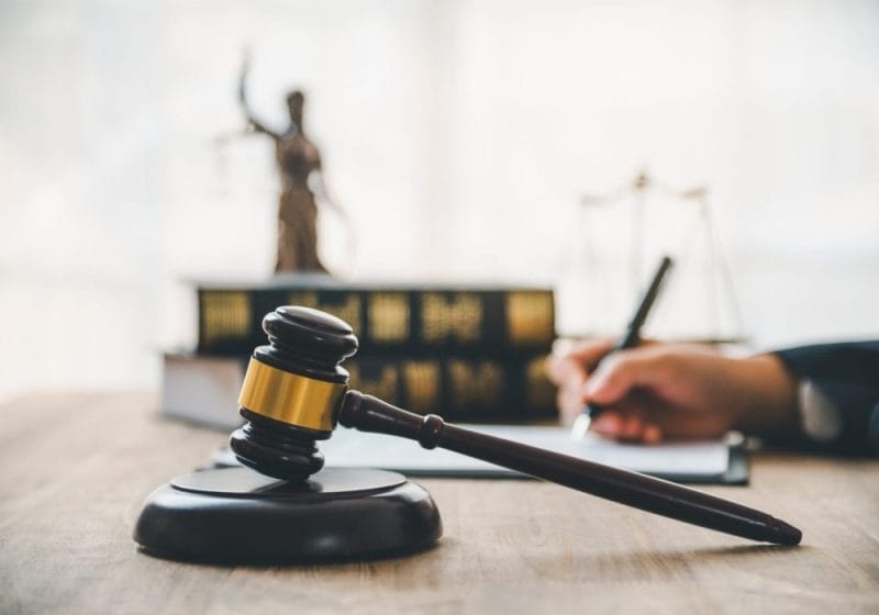 Solicitor signing documents with a gavel in the foreground